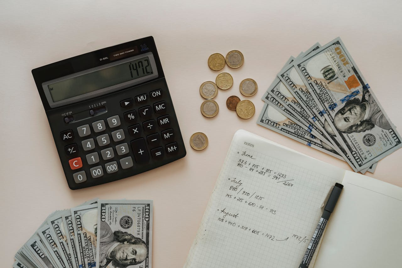 Home Flat lay of calculator, cash, coins, and handwritten notes for budget planning.