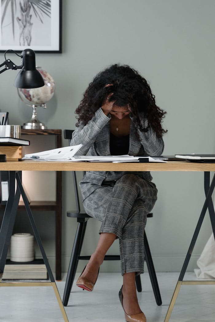 Home A frustrated businesswoman sitting at a desk, stressed in a modern office setting.