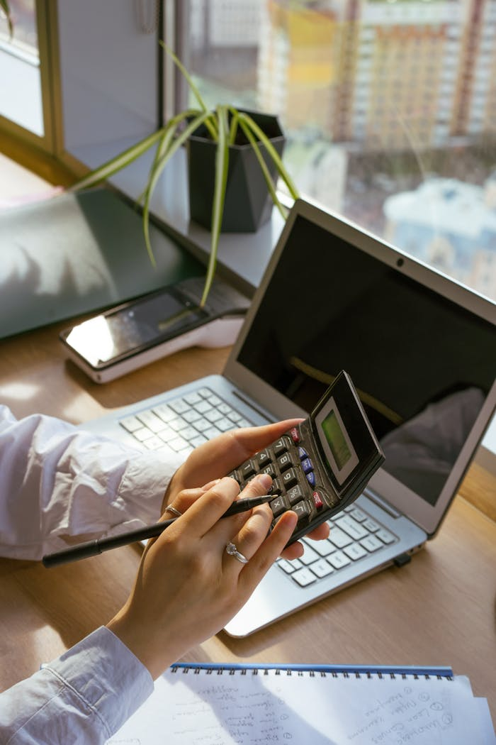 Home Person calculating at desk with laptop and notebook. Ideal for business and finance themes.